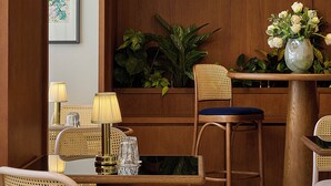 Un intérieur moderne avec des lambris en bois, un coin repas avec des chaises en rotin, une table avec une lampe et un luminaire suspendu.