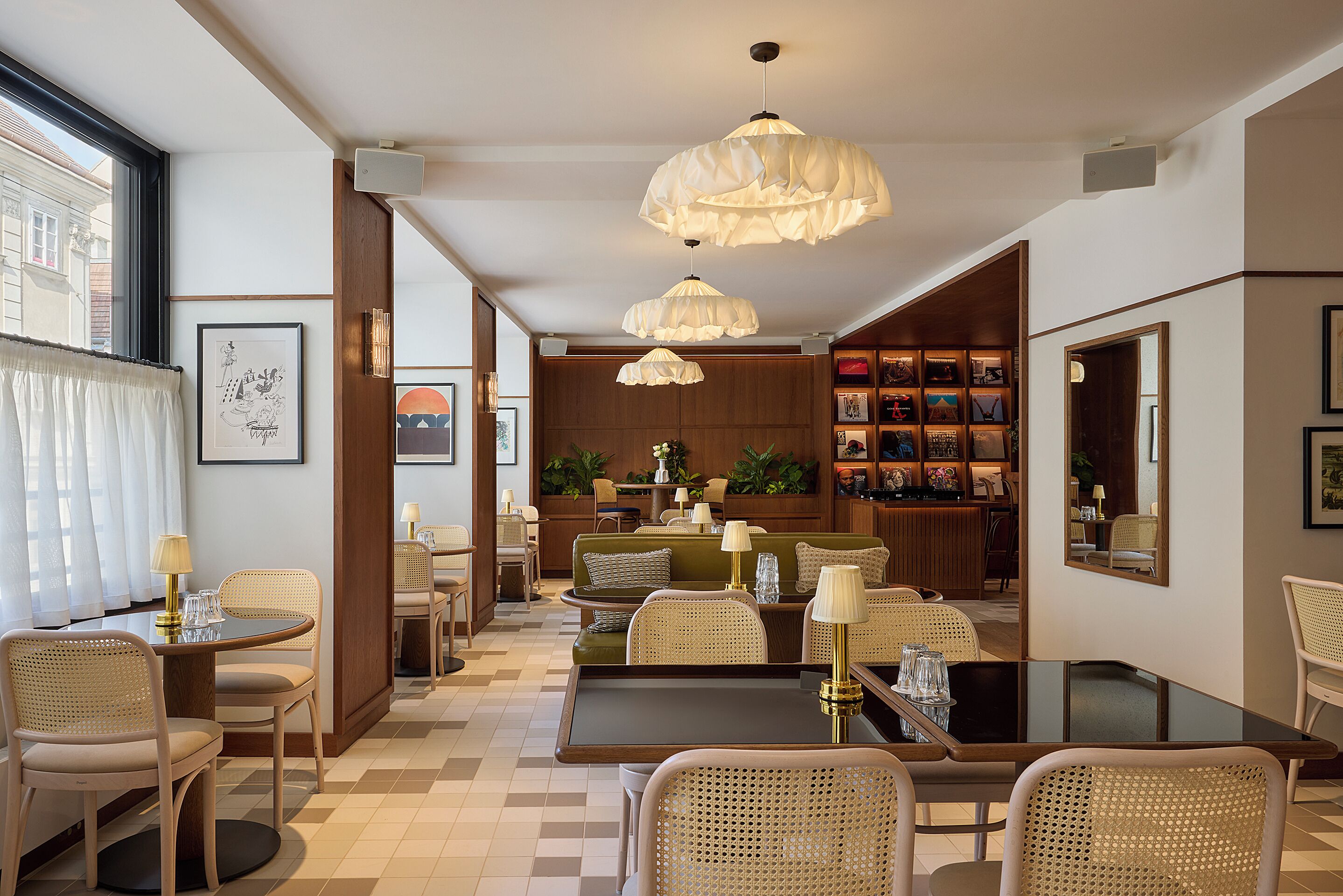 A hotel lobby with a dining area, seating arrangements, and a bookshelf.