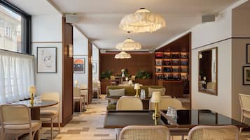 A hotel lobby with a dining area, seating arrangements, and a bookshelf.