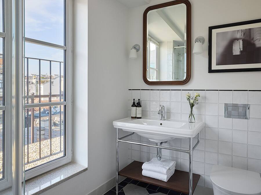 Een badkamer met een raam, een wastafel, een spiegel en een toilet.