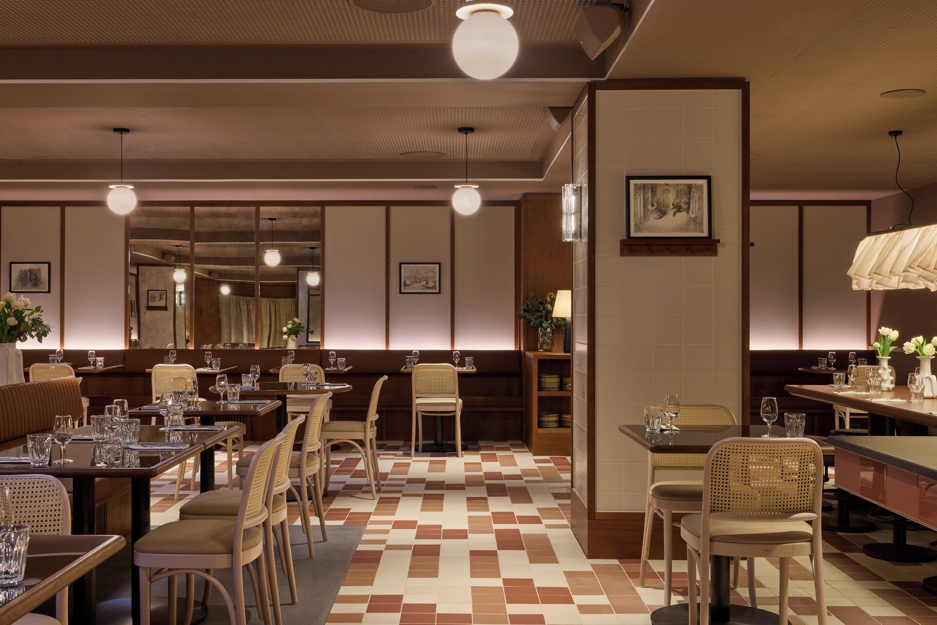 Un ristorante con diversi tavoli e sedie, un pavimento decorato e luci a sospensione.