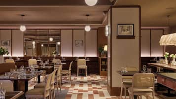 Un ristorante con diversi tavoli e sedie, un pavimento decorato e luci a sospensione.