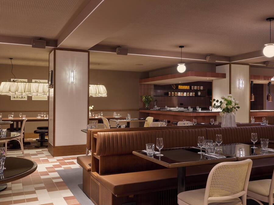 A restaurant with booths, round tables, and a bar area.