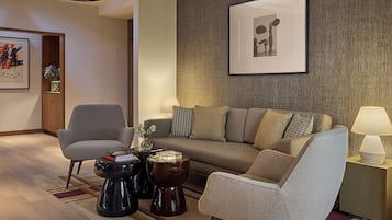 Uma sala de estar moderna com um sofá, poltronas, uma mesa de centro e uma luminária.