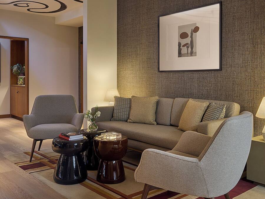 A modern living room with a sofa, armchairs, a coffee table, and a lamp.