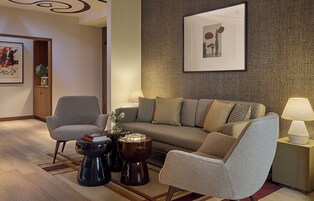 Uma sala de estar moderna com um sofá, poltronas, uma mesa de centro e uma luminária.