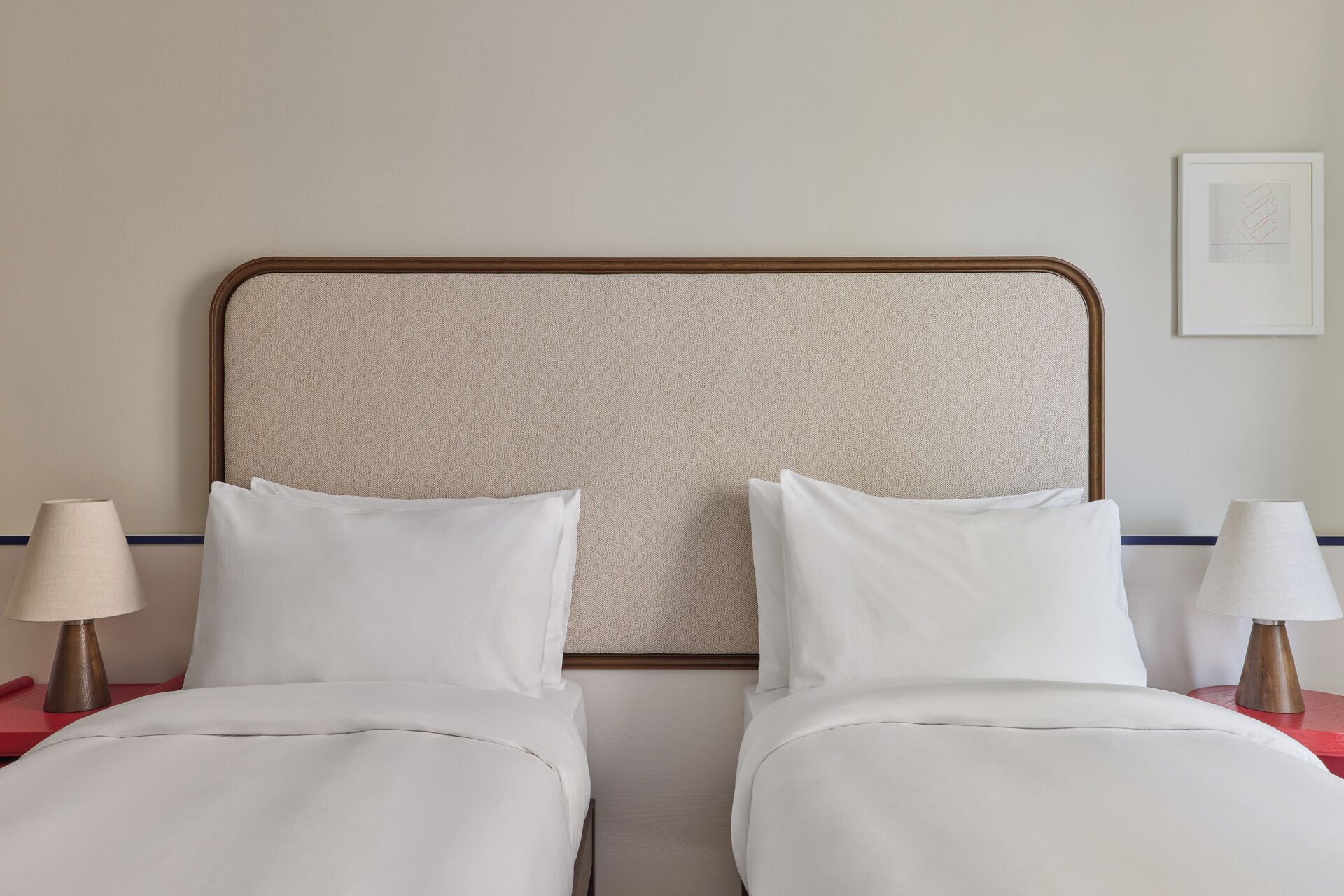 Un letto matrimoniale con testiera in legno, due comodini con lampade e un quadro appeso al muro.