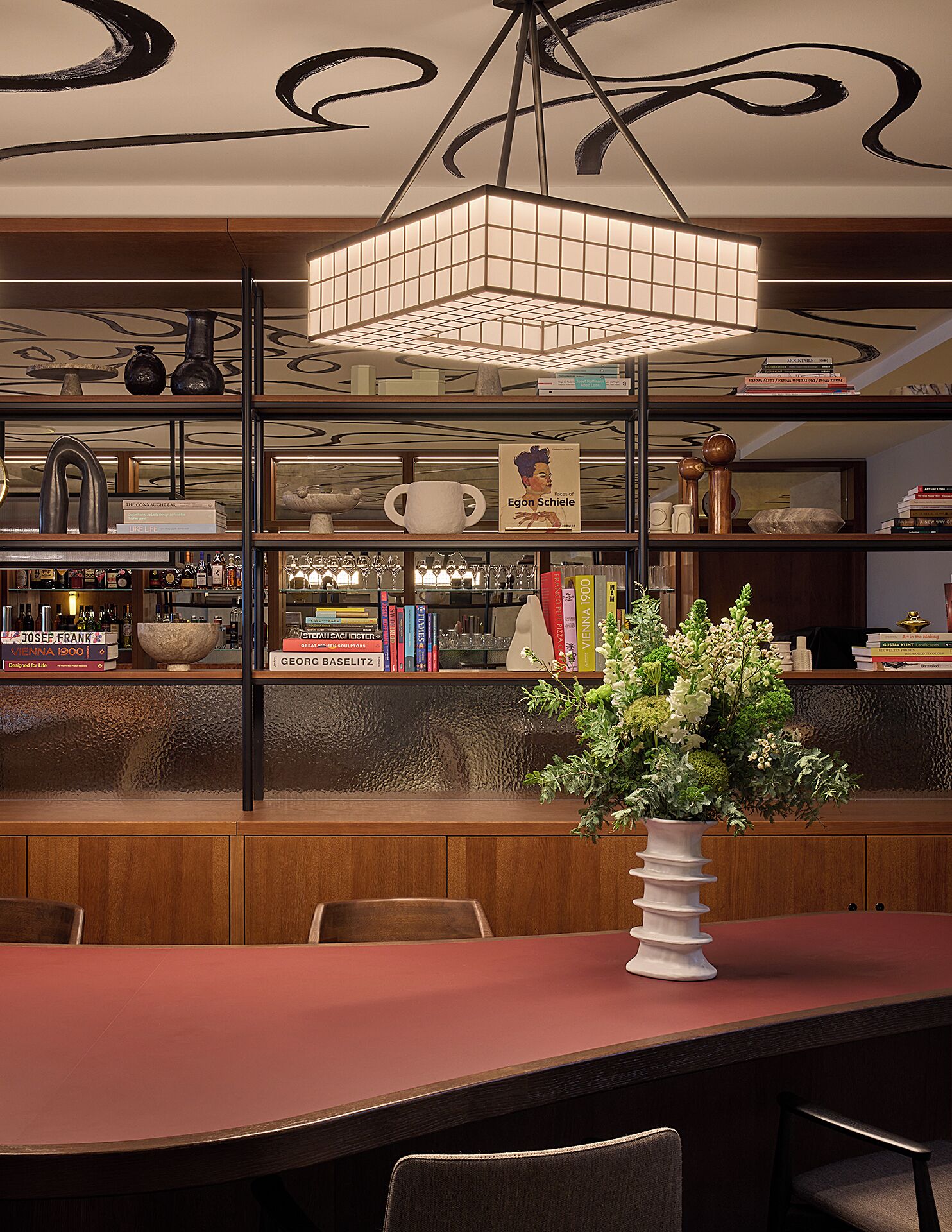 Interior de un restaurante con una zona de bar, estanterías y un jarrón decorativo en la barra.