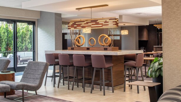 A modern bar area with a central island, bar stools, and a contemporary light fixture.