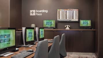 A boarding pass desk with multiple computer monitors, a keyboard, and office chairs.
