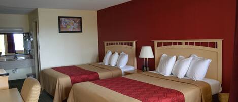 A hotel room with two beds, a desk, and a chair.