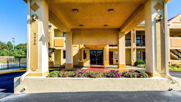 A hotel entrance with a covered walkway, columns, and a flower bed.