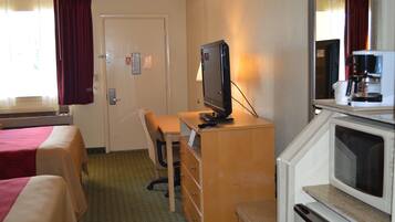 A hotel room with two beds, a desk with a television, a dresser, and a microwave.