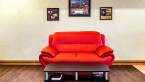 A red sofa, a black coffee table, and three framed pictures on the wall.
