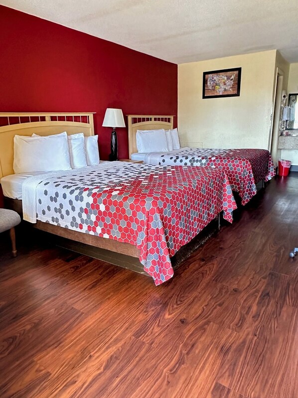 Ein Hotelzimmer mit zwei Betten, Holzboden und einer roten Akzentwand.