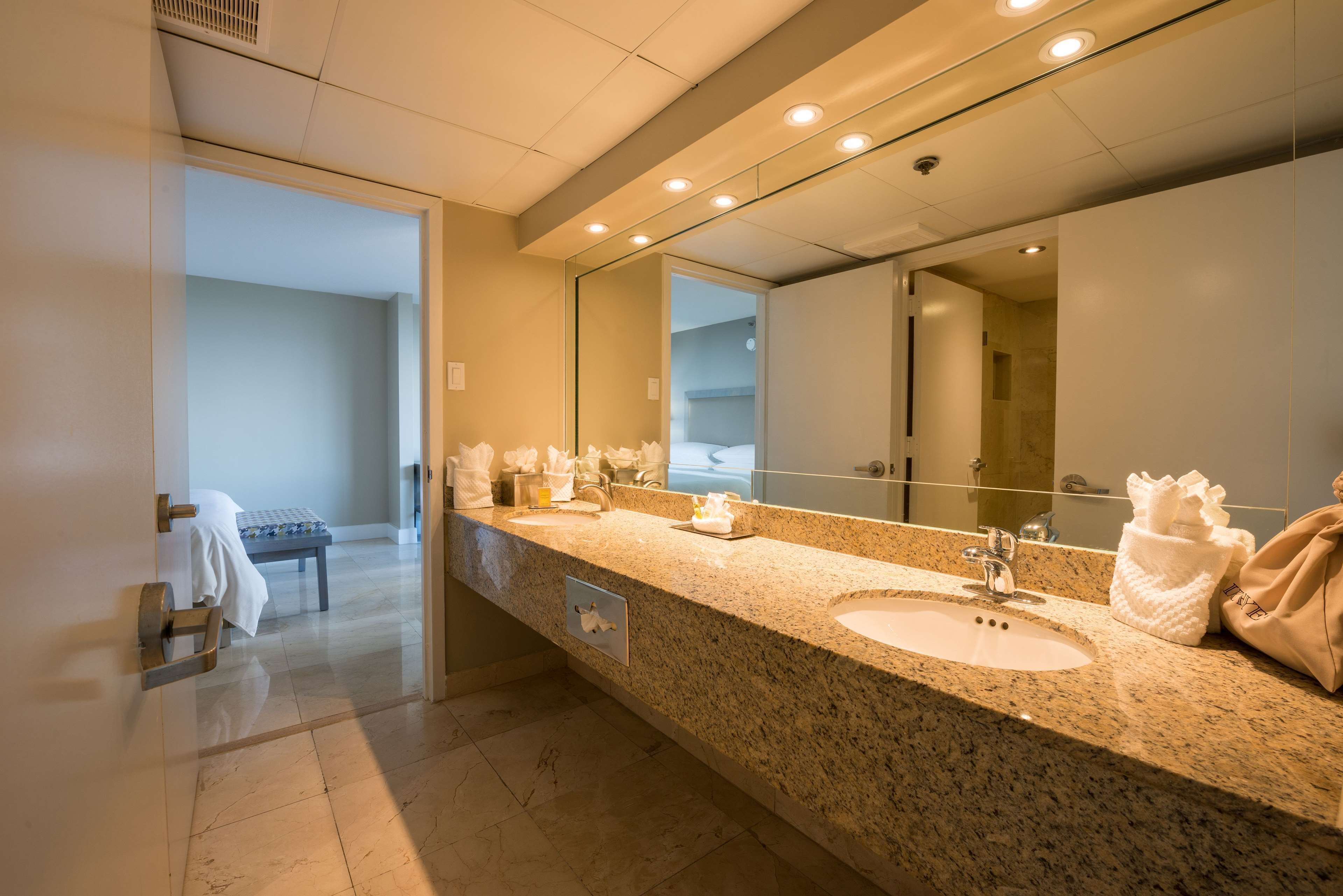 Une salle de bain moderne avec un grand miroir, deux lavabos et un banc.