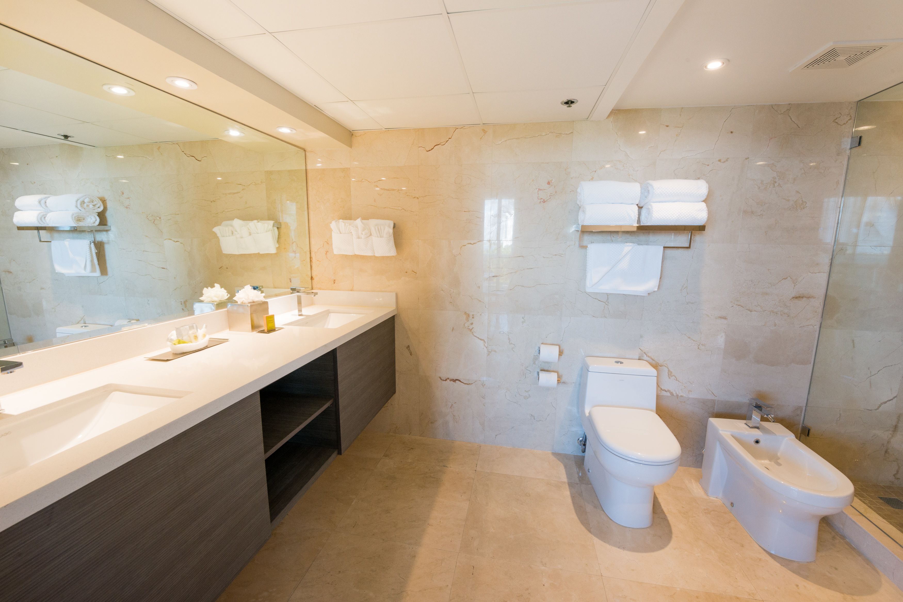 Ein modernes Badezimmer mit großem Spiegel, Waschbecken, Toilette und Bidet.