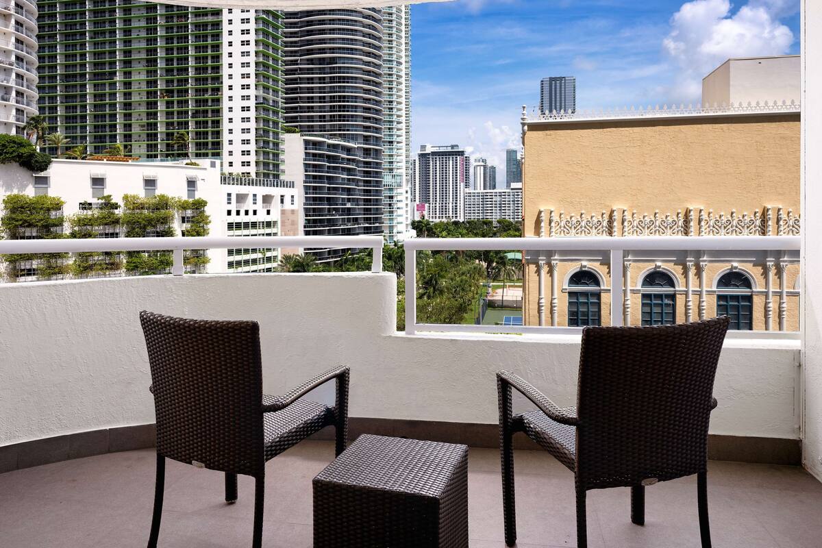 A balcony with wicker furniture and a view of modern high-rise buildings.