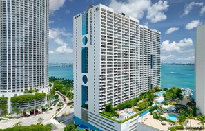 Un grand hôtel à plusieurs étages, doté d’une piscine et offrant une vue sur l’océan.