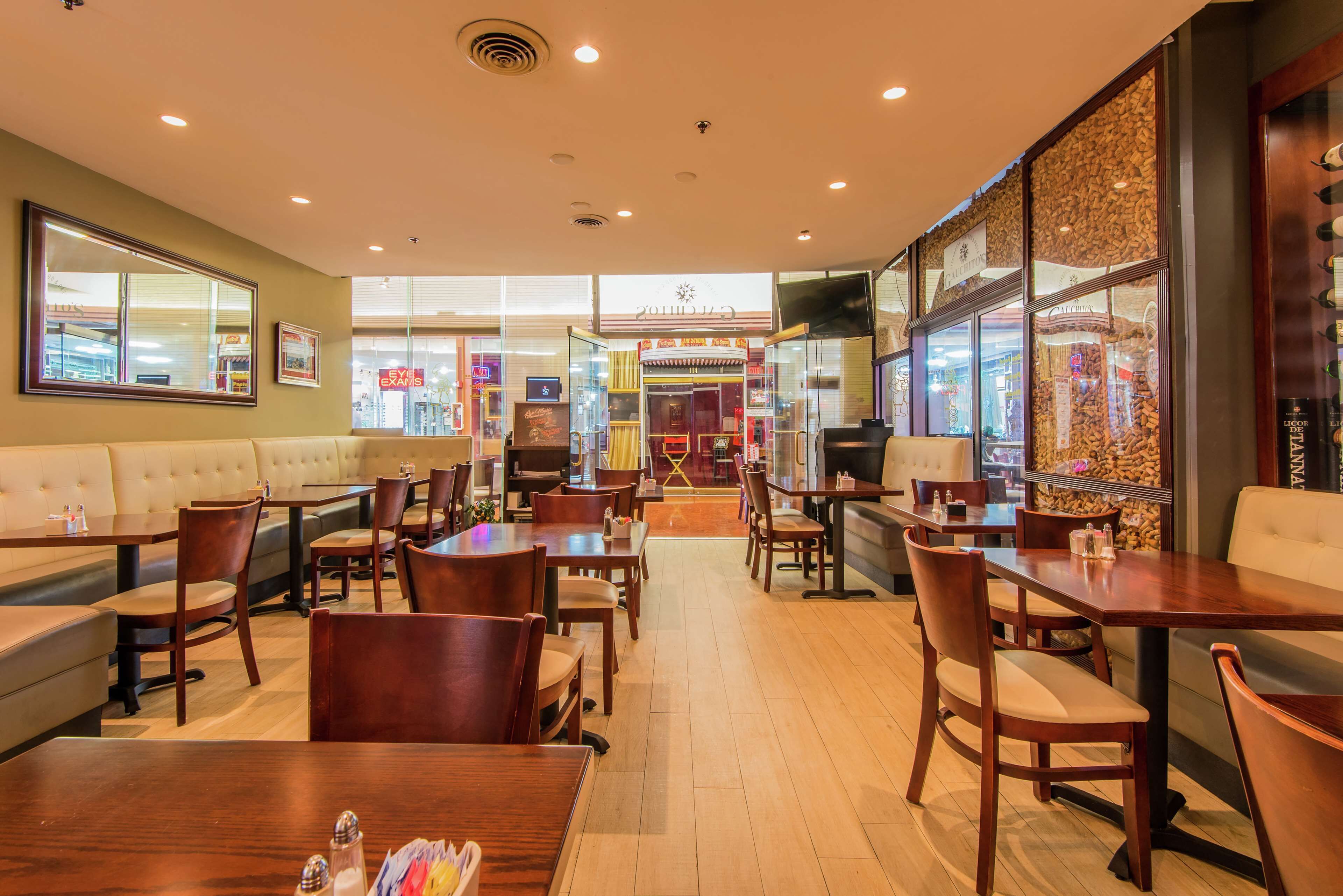 A restaurant with booths, tables, and chairs. There are signs for 'Eye Exams' and 'Eyeglasses' visible through the windows.