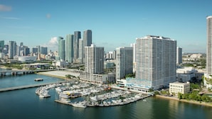 A marina with boats docked, surrounded by high-rise buildings and a clear sky. - DoubleTree by Hilton Grand Hotel Biscayne Bay (Miami)