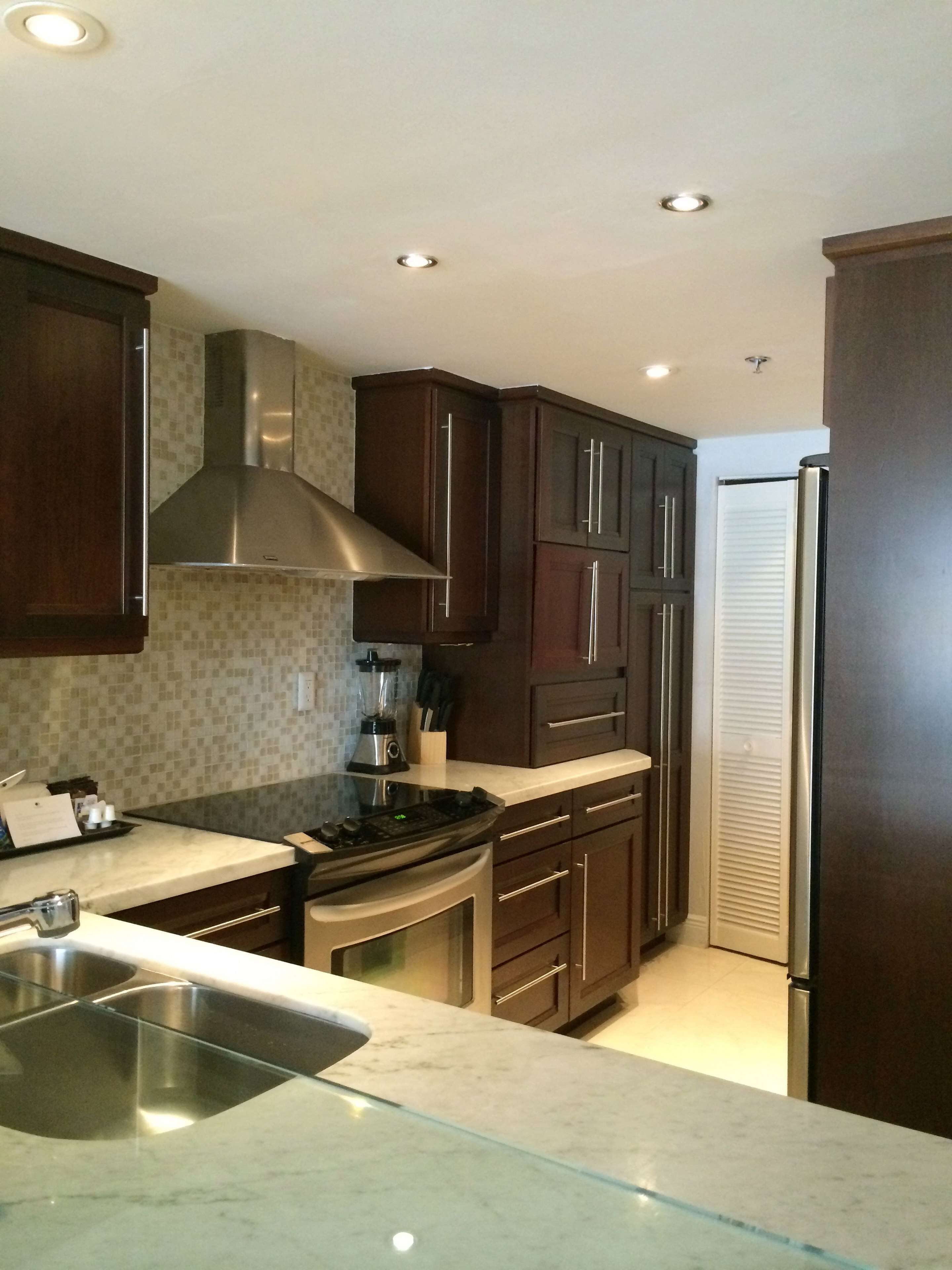 A modern kitchen with dark wooden cabinets, stainless steel appliances, and a marble countertop.