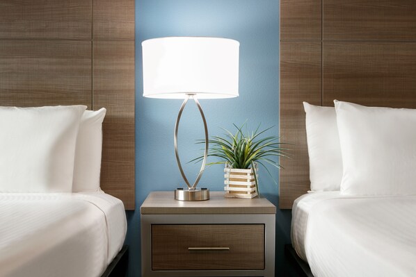 Relax in a stylish room with a neatly made bed, bedside table, and potted plant.