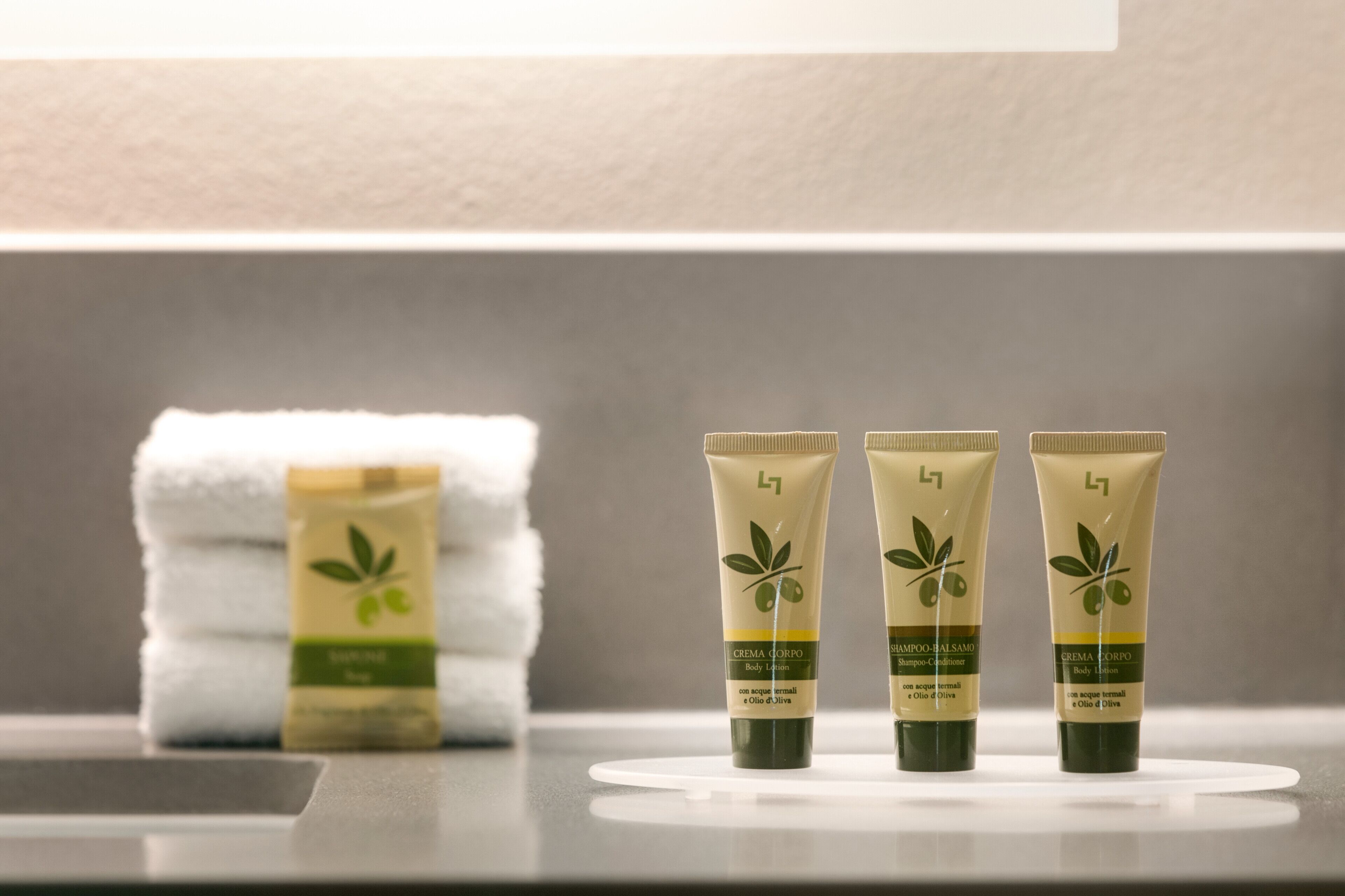 Three tubes of body lotion and a stack of towels on a counter.