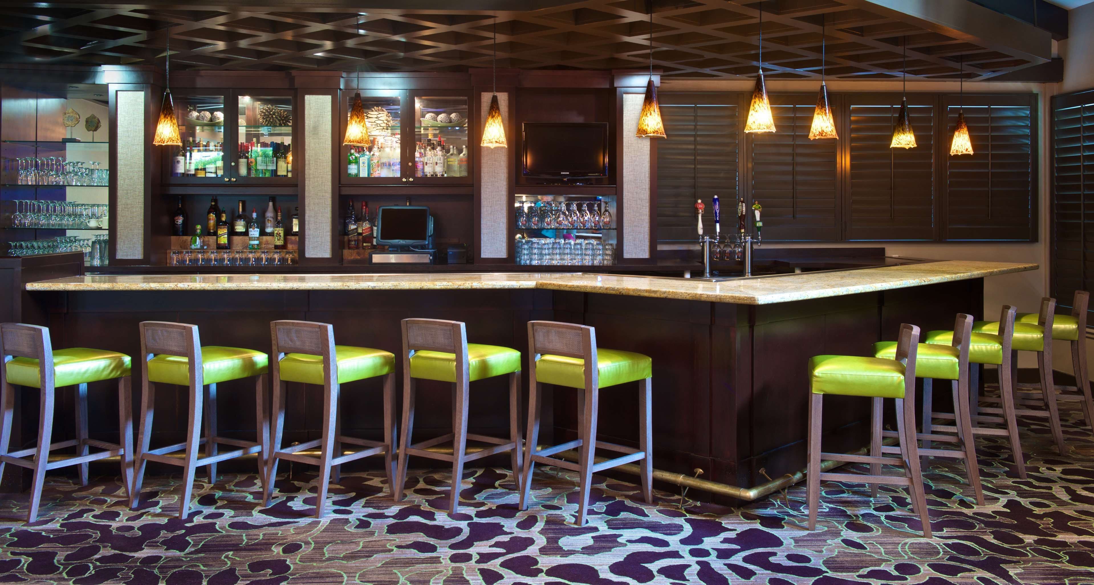 A bar area with a counter, stools, and hanging lights.