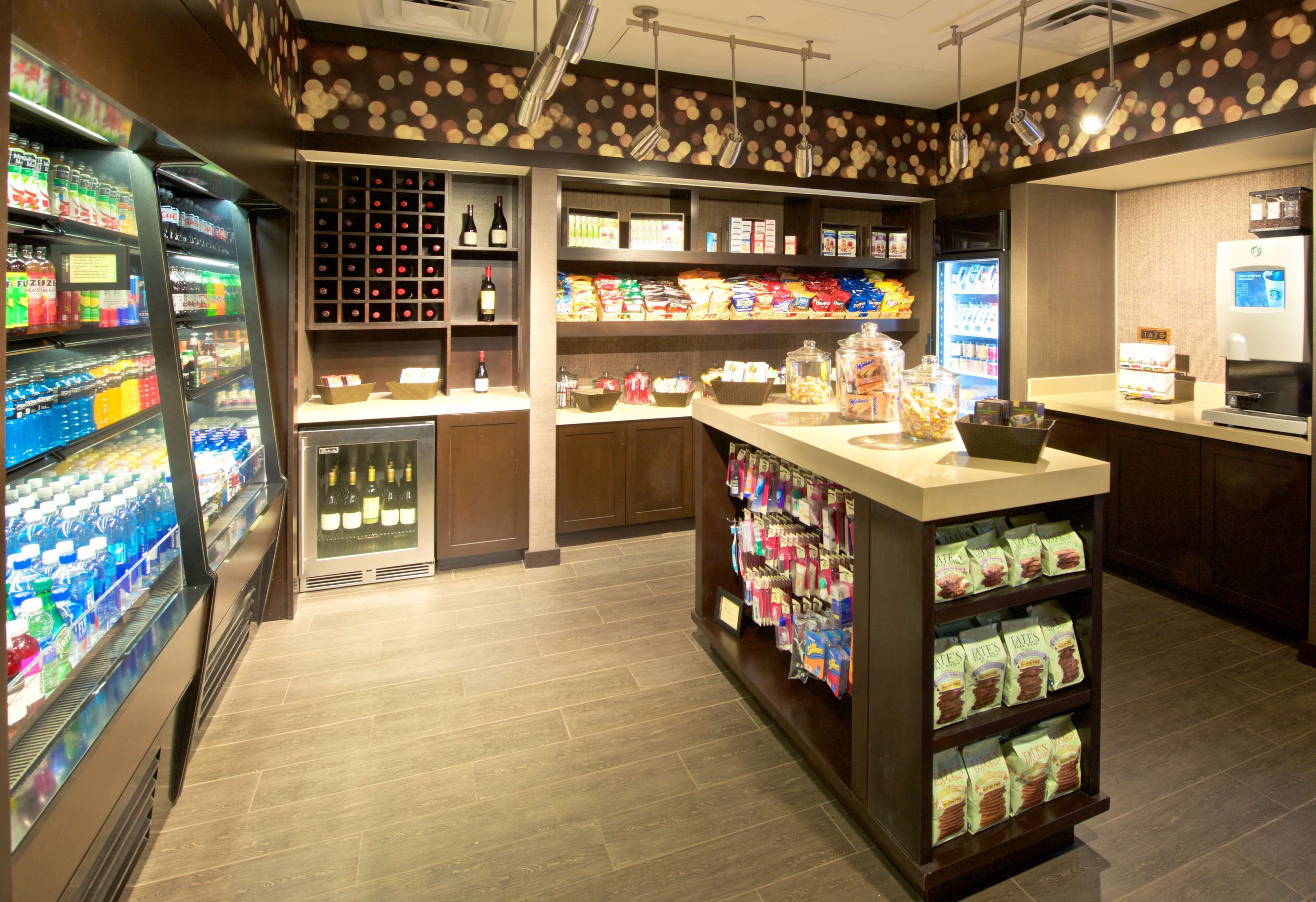 A well-lit convenience store with refrigerated beverages, snacks, and a coffee machine.