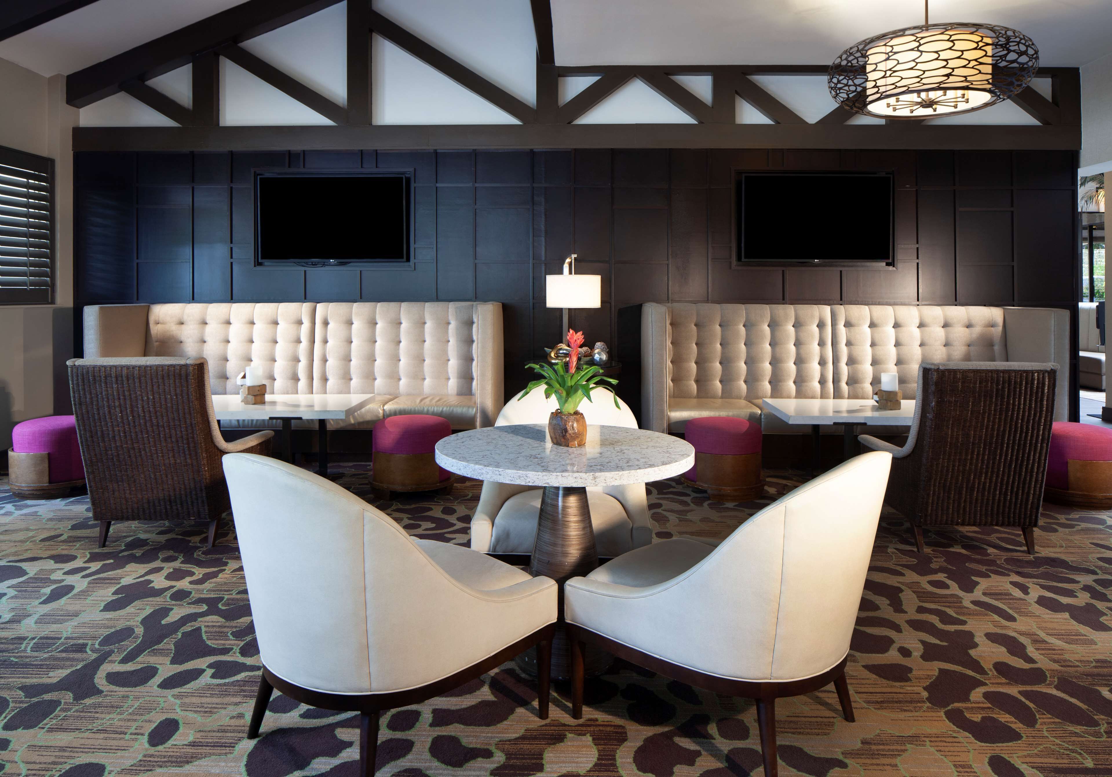 A lobby with a round table, two sofas, and a television on the wall.