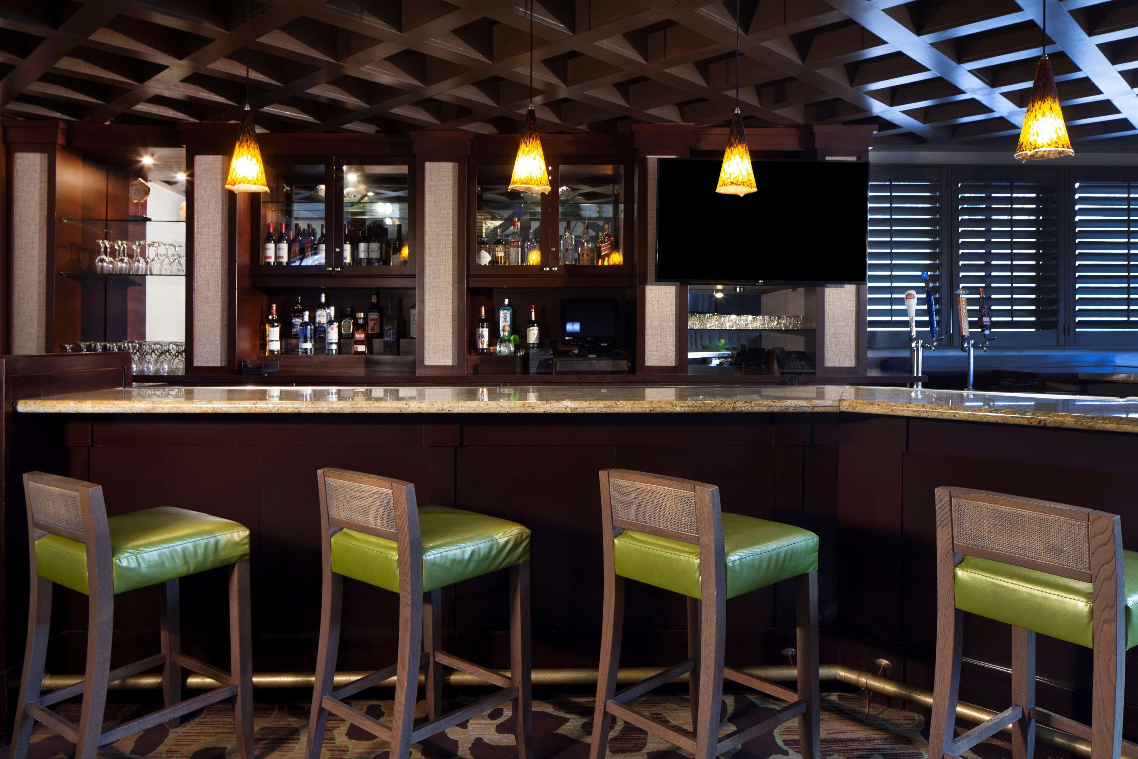A bar area with a counter, stools, and hanging lights.
