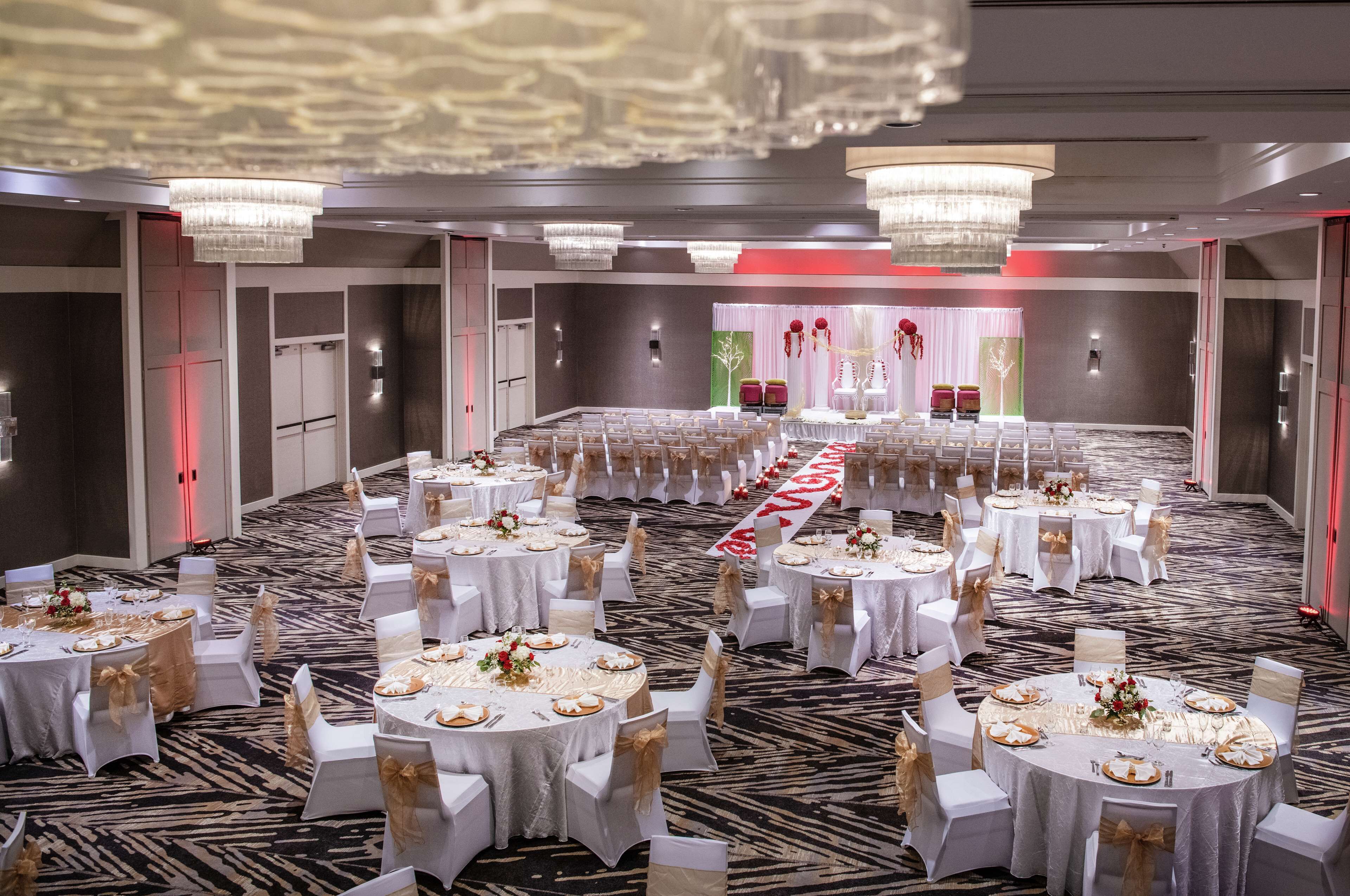 Une salle de banquet avec des tables rondes, des nappes blanches et des rubans dorés.