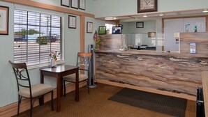 A reception area with a marble counter, framed certificates on the wall, and a window with blinds. - Americas Best Value Inn Ozona (Ozona)