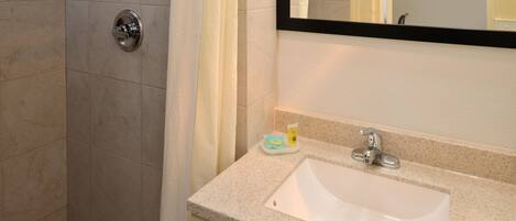 Un baño con ducha, lavamanos y espejo.