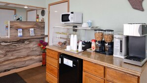 A kitchen area with a microwave, coffee maker, and a refrigerator. There are also cups and a coffee dispenser on the counter. - Americas Best Value Inn Ozona (Ozona)