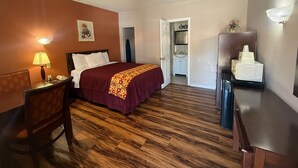 A hotel room with a bed, a desk with a lamp, a chair, a microwave, and a small refrigerator. - Americas Best Value Inn Ozona (Ozona)