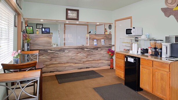 A kitchen with a marble island, wooden cabinets, a microwave, and a dishwasher. - Americas Best Value Inn Ozona (Ozona)