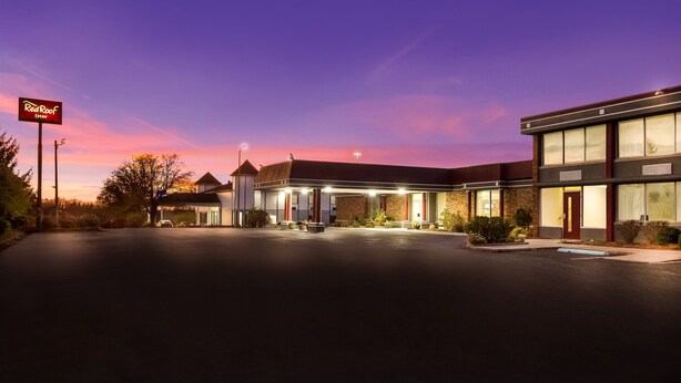 A Red Roof Inn with a spacious parking lot and a two-story building featuring a brick facade and large windows. - Red Roof Inn Winchester - Lexington East (Winchester)