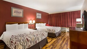 A hotel room with two beds, a wooden floor, a desk with a lamp, and a TV. - Red Roof Inn Winchester - Lexington East (Winchester)