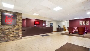 A Red Roof Inn reception area with a stone wall, a reception desk, and a sign indicating free WiFi in all rooms. - Red Roof Inn Winchester - Lexington East (Winchester)