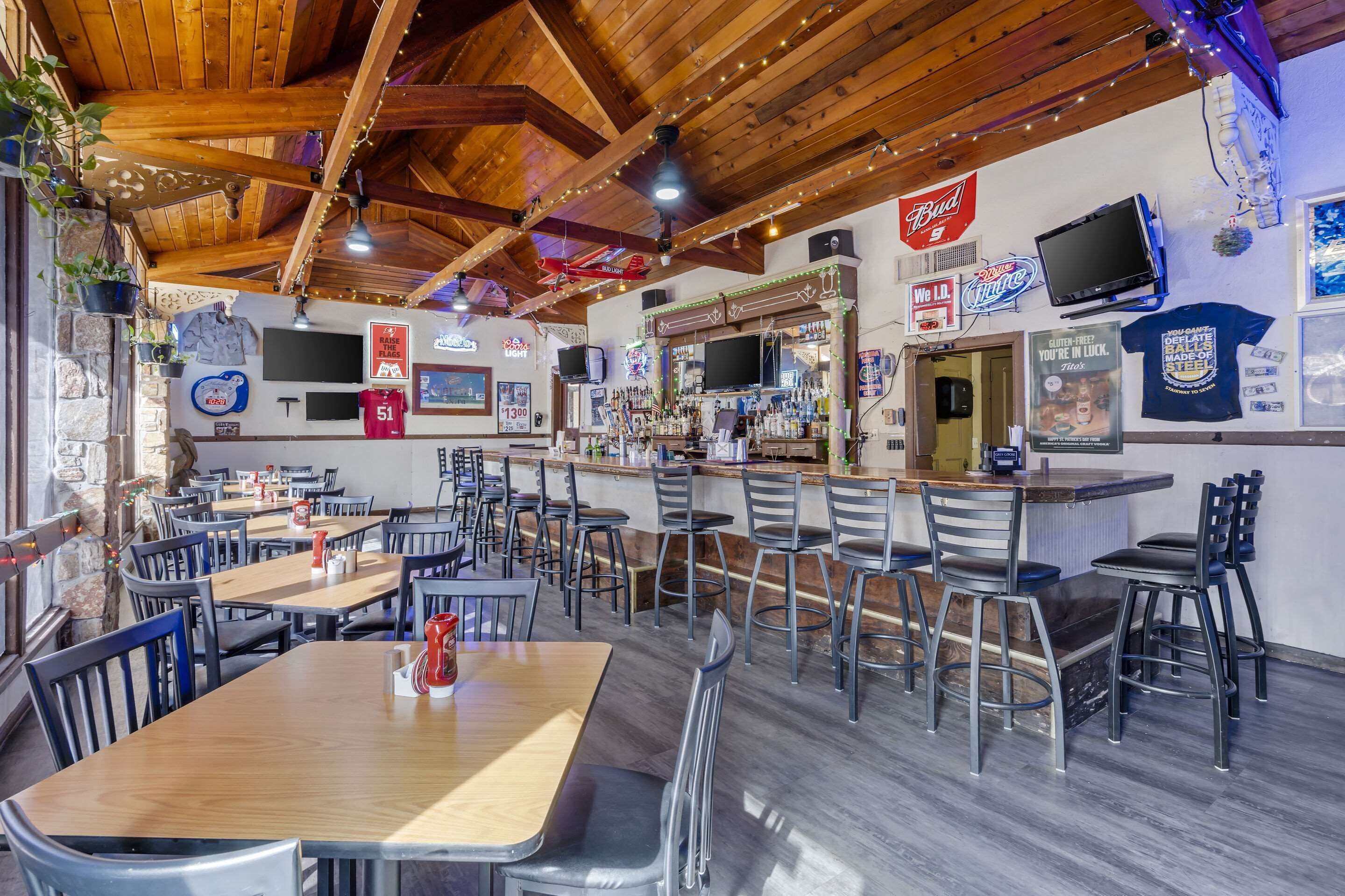 A restaurant with wooden ceiling beams, bar area, and multiple seating arrangements.