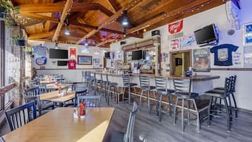 A restaurant with wooden ceiling beams, bar area, and multiple seating arrangements.