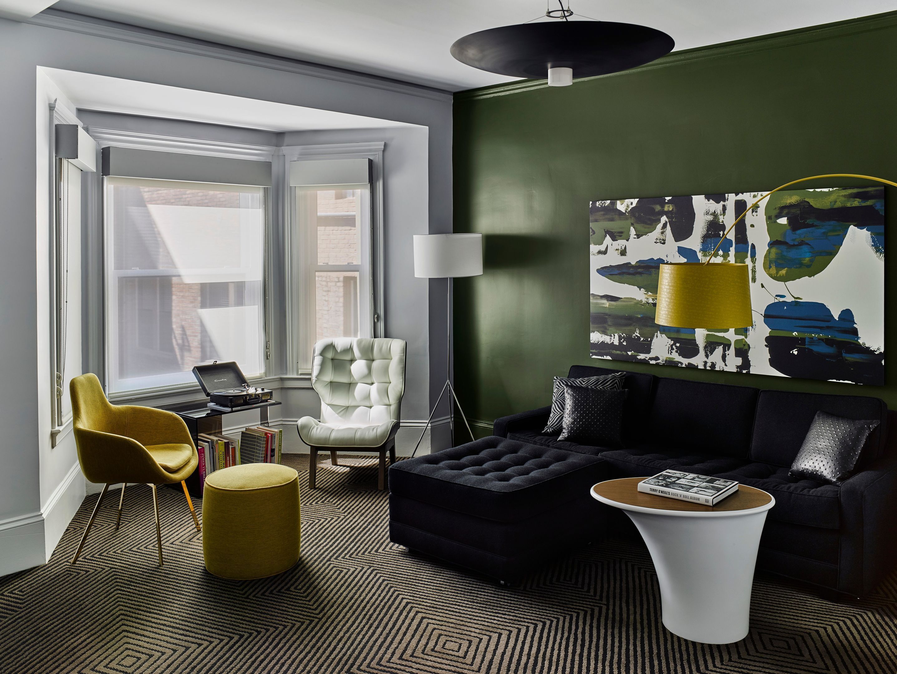 A modern living room with a sofa, armchair, ottoman, and a coffee table.