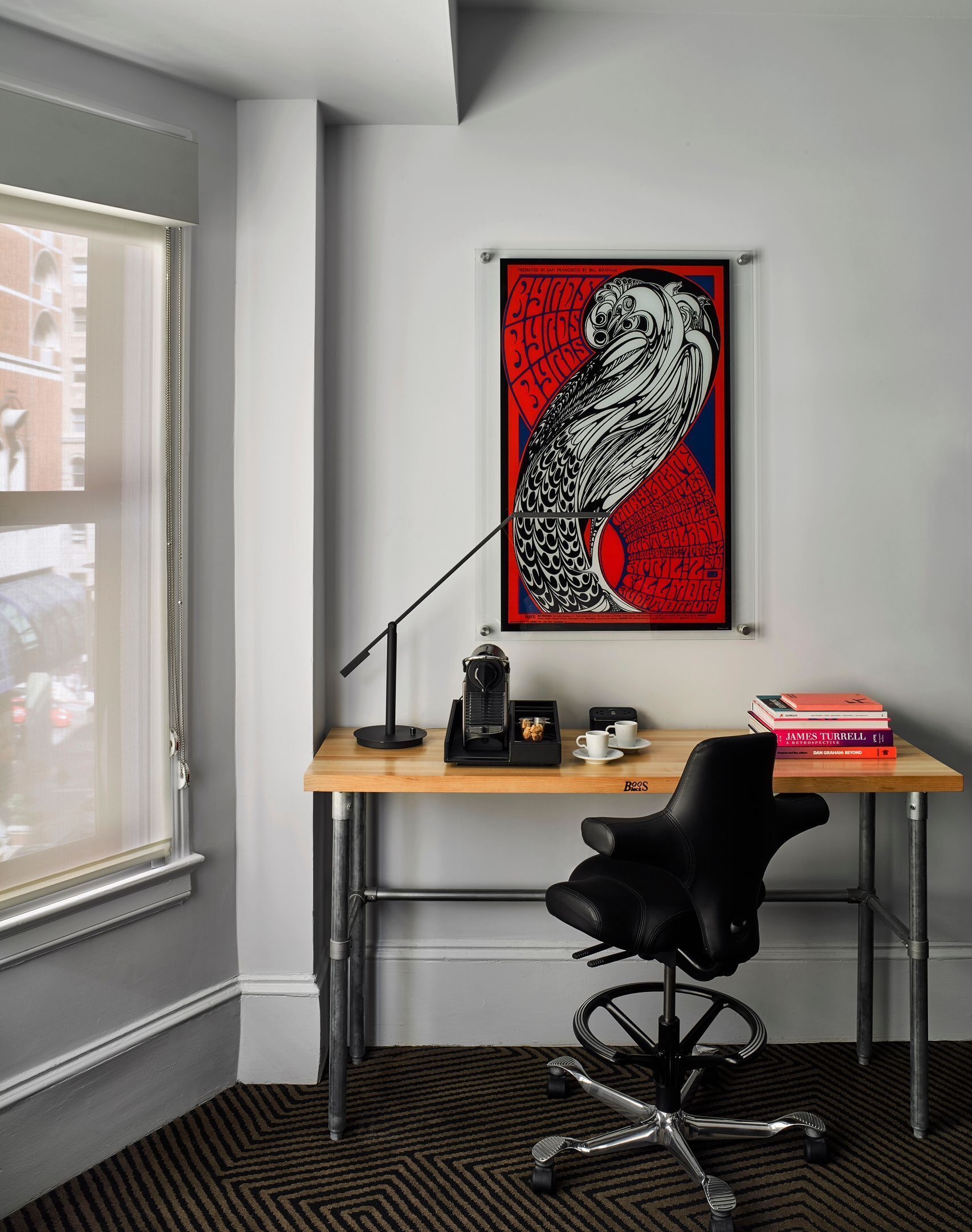 A modern office space with a desk, chair, coffee machine, and a framed artwork on the wall.
