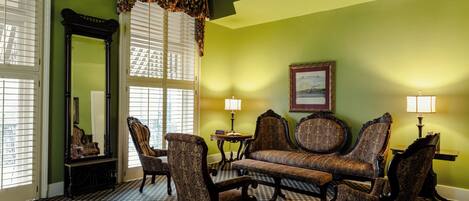A room with a checkered floor, a sofa, armchairs, and two lamps.