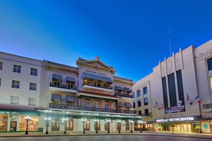 Un hotel histórico con una fachada clásica, varios balcones y un llamativo cartel luminoso.