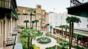 A courtyard with a central fountain, surrounded by palm trees and potted plants.