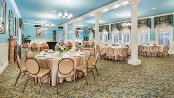 A spacious banquet hall with round tables, chairs, and a patterned carpet.