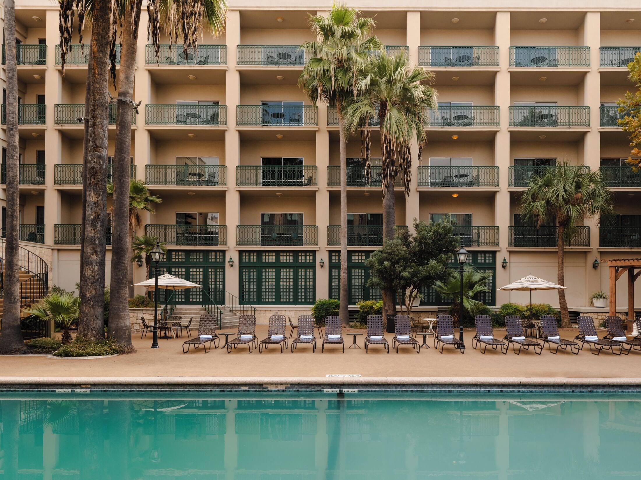 Un hotel con varios balcones, piscina y mobiliario para exteriores.